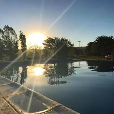 a pool of water with the sun in the background at Casa de campo La Querencia in Villa Cura Brochero