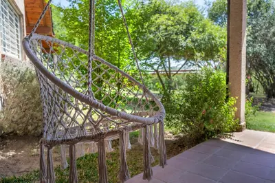 a metal swing hanging from a porch at Casa Arboles De Tala con parque amplio in Villa General Belgrano