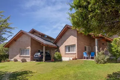 a house with a car parked in front of it at Casa Arboles De Tala con parque amplio in Villa General Belgrano