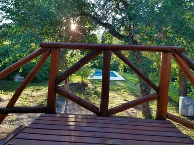 a wooden bridge with the sun shining through the trees at El diquecito monoambiente in Casa Bamba