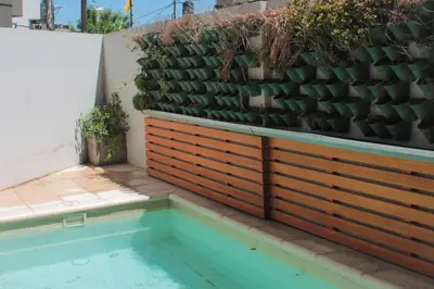 a retaining wall with a pool and a fence with plants at Dpto con pileta y cochera Güemes - Nueva Córdoba -Seguridad 24 hs Terraza y asadores!! Balcón Panorámico! in Cordoba