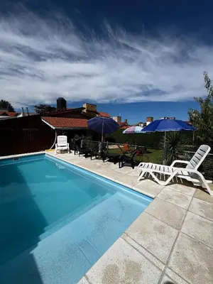 a swimming pool with two lawn chairs and umbrellas at Complejo LA MERLINA in Merlo