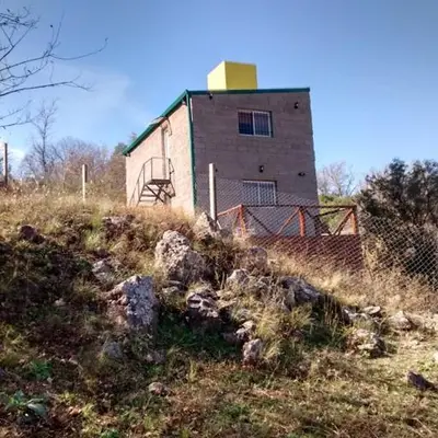 a building on the side of a hill with rocks at Departamento Estancia Vieja 74 PA in Estancia Vieja