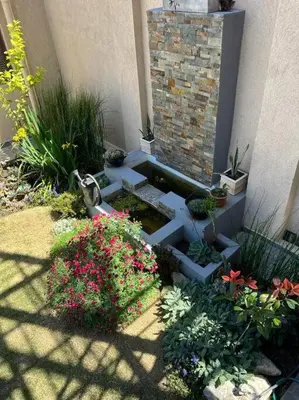 a garden with flowers and plants in front of a building at LUMINOSO piso con jacuzzi in Alta Gracia