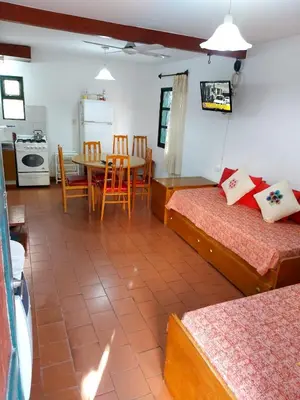 a room with two beds and a table and a kitchen at Castillo Del Lago - Carlos Paz - dep17 in Villa Carlos Paz
