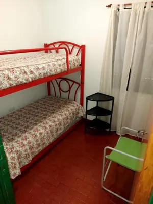 a bedroom with two bunk beds and a green chair at Castillo Del Lago - Carlos Paz - dep17 in Villa Carlos Paz