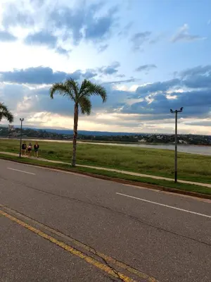 two people sitting on the side of a road with a palm tree at Castillo Del Lago - Carlos Paz - dep17 in Villa Carlos Paz